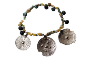  Stikla kreļļu kaklarota ar bronzas zvārguļiem. Atrasta sievietes apbedījumā Turaidas Baznīckalna kapsētā.13. gadsimta pirmā puse. SM 3943 